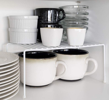 the wire shelf with two mugs underneath it and small bowls on top of it 