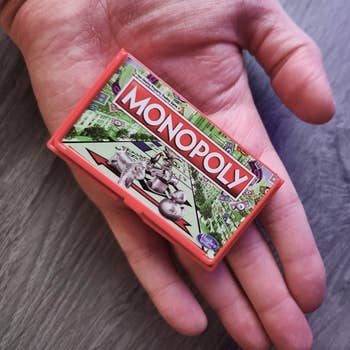 the miniature version of monopoly in a reviewer's hand for scale