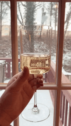 A cylinder shaped flat rimmed wine glass with bubbling prosecco in it 