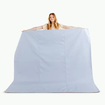 model holding up extra large baby blue picnic blanket