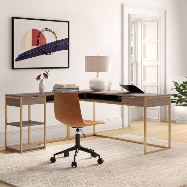 the wood and gold l-shaped desk with books and a laptop on top