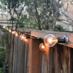 reviewer close-up of the lit string bulbs attached to a wooden fence