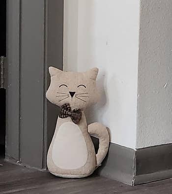 a reviewer photo of the door stopper that's shaped like a cat wearing a bow tie 
