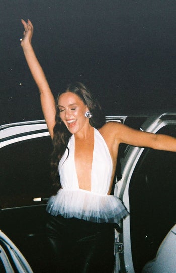 model wearing white halter top with tulle on the bottom getting out of a car
