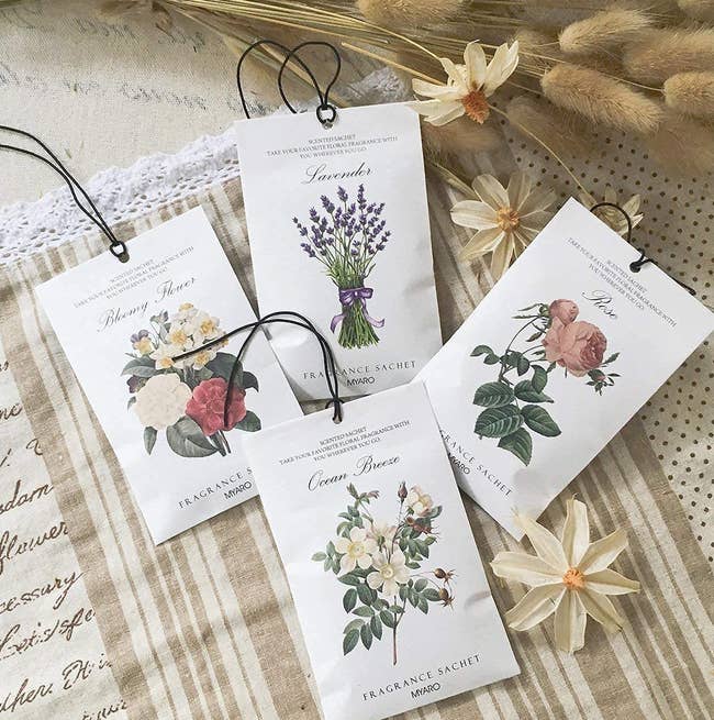 four of the floral scented sachets on some linen surrounded by dried flowers