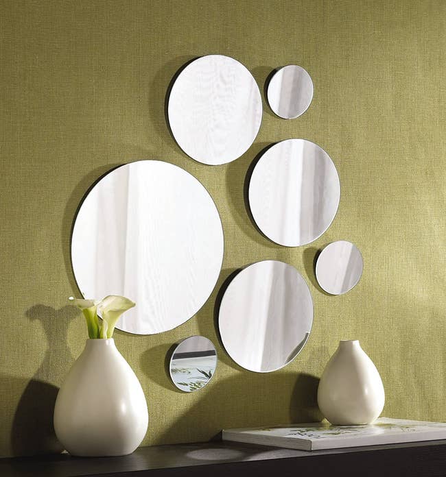 seven round mirrors of various sizes hanging on a wall above a dresser