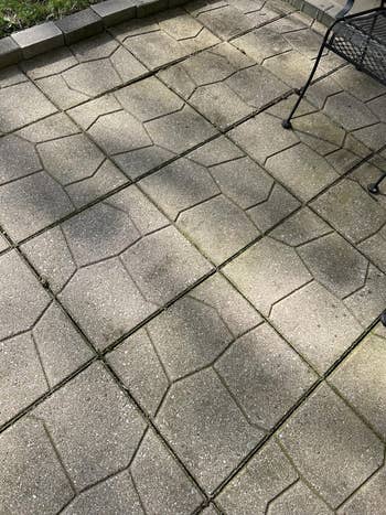 Stone patio with geometric tile signifier   and portion  of a metallic  chair