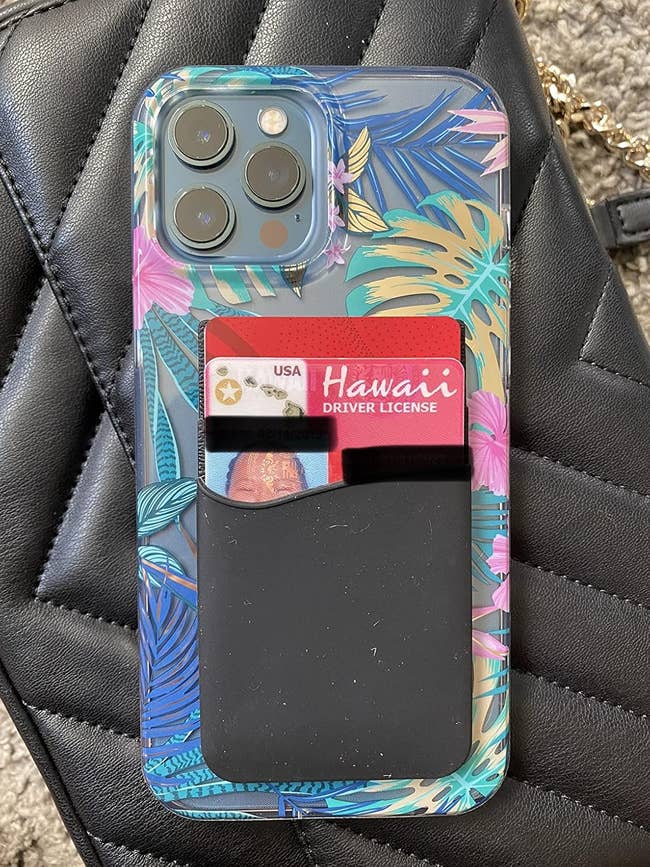 An iPhone with a black cardholder pouch attached to the back