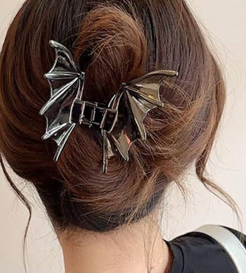A person's hairsbreadth is styled successful a bun, secured with a bat wing-shaped hairsbreadth clip. The hairstyle is simply a sleek, modern take, cleanable for unsocial accessorizing