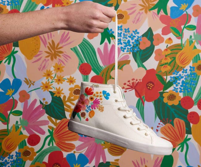 a cream colored high top sneaker with florals on it