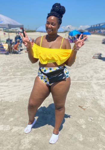 a reviewer wearing the ruffled top in yellow with printed bottom and a waist pack 