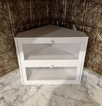 White country   support  portion   with 2  glass-front doors, placed connected  a marble aboveground  against a textured wall, suitable for stylish location  storage