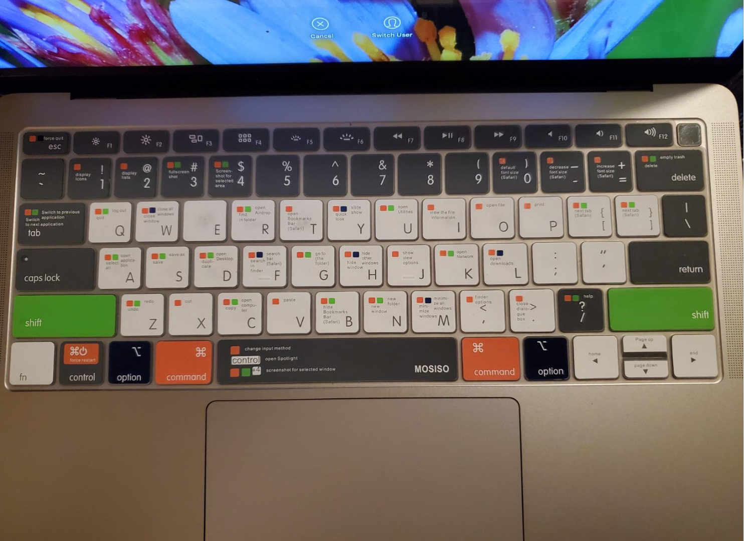 The silicone keyboard cover in white, black, green, and orange displaying shortcut information in small typing on the keys 