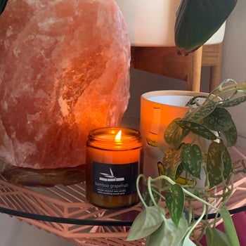 reviewer photo of their lit bamboo grapefruit-scented candle next to a rock salt lamp