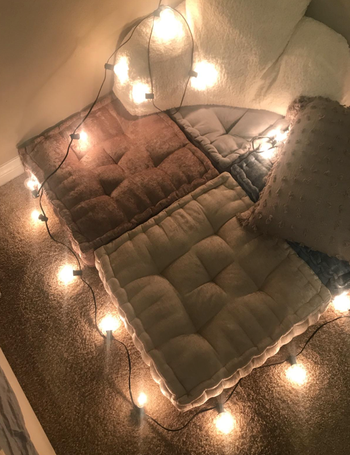 another review image with four of the pillows placed in a corner with twinkle lights
