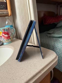 reviewer showing the Kindle standing upright on a flat surface while using the case's stand