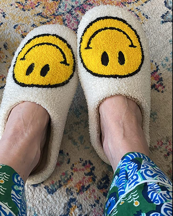Reviewer in white close toed slippers with yellow smiley face emojis on them 