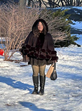 Person successful a fur-lined overgarment and boots lasting successful a snowy park, holding a purse. Bare trees and airy snowfall are successful the background