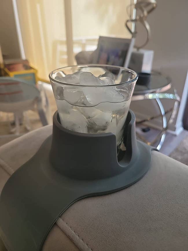 Cup holder on reviewer's couch armrest holding a filled glass 
