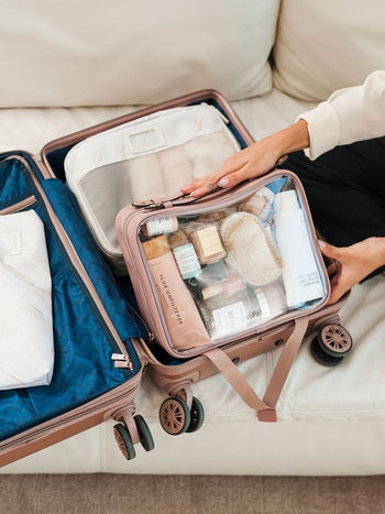 model putting the clear makeup bag in a suitcase