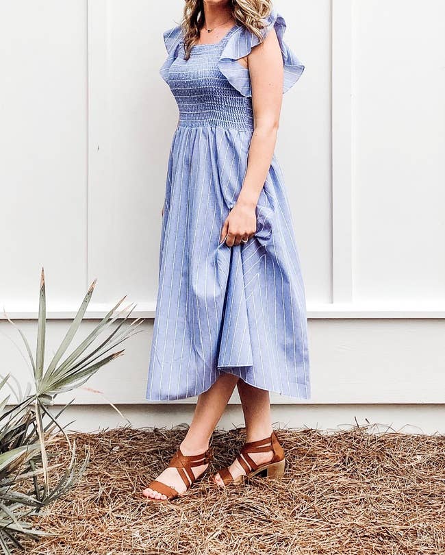 a reviewer wearing the blue striped smocked linen dress