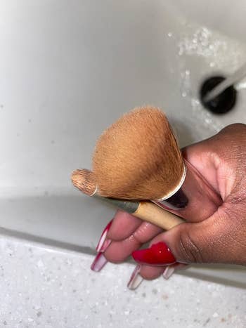 a reviewer holding up two dirty makeup brushes