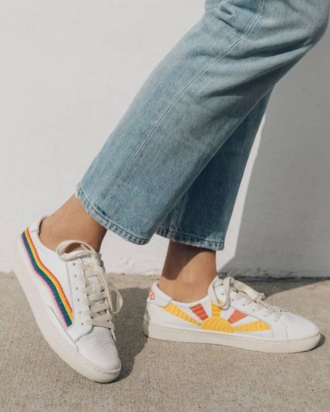 White sneakers with embroidered rainbow along the outsides and embroidered sun in yellow and orange along the insides