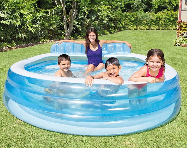 Children enjoying an inflatable excavation outdoors, smiling and splashing with a young pistillate supervising