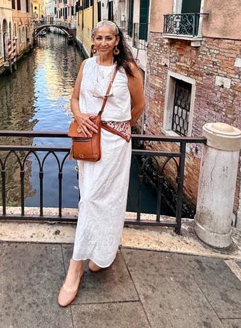 Person successful a achromatic summertime formal posing by a canal successful a historical metropolis setting
