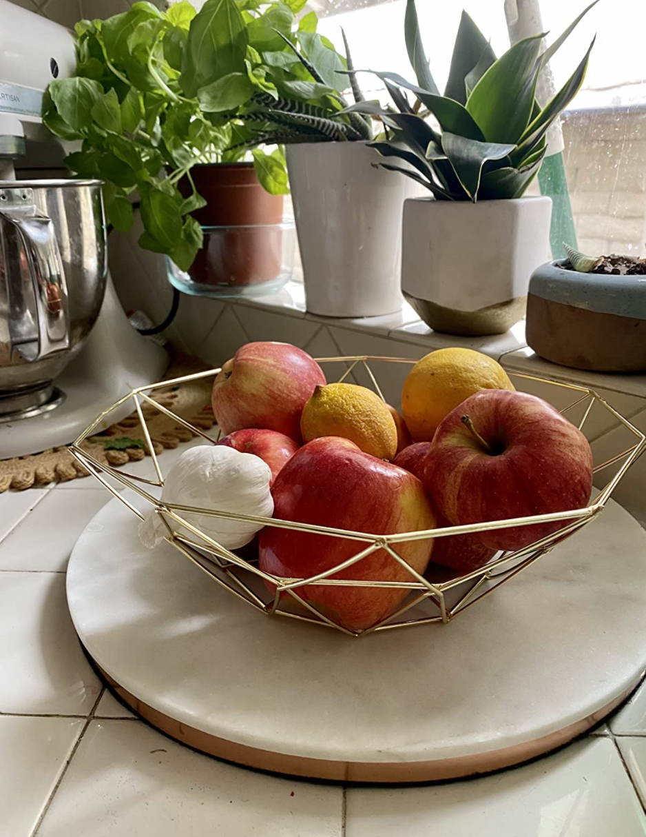 gold geometric wire bowl with fruit inside on a counter 