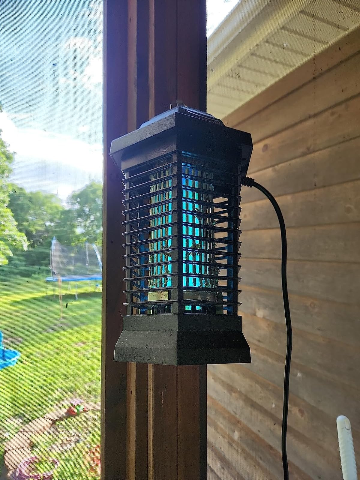 a reviewer photo of the bug zapper lantern hanging on a patio 