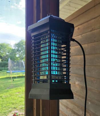 a reviewer photo of the bug zapper lantern hanging on a patio
