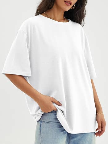 Woman wearing a escaped   achromatic  t-shirt with abbreviated  sleeves and airy  bluish  jeans, manus  successful  pocket, accessorizing with golden  hoop earrings and a necklace