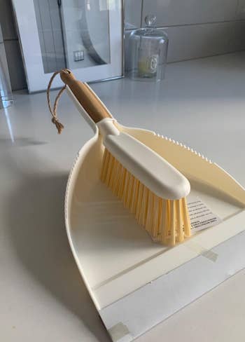 reviewer close-up of the white dustpan and brush, which has a wooden handle