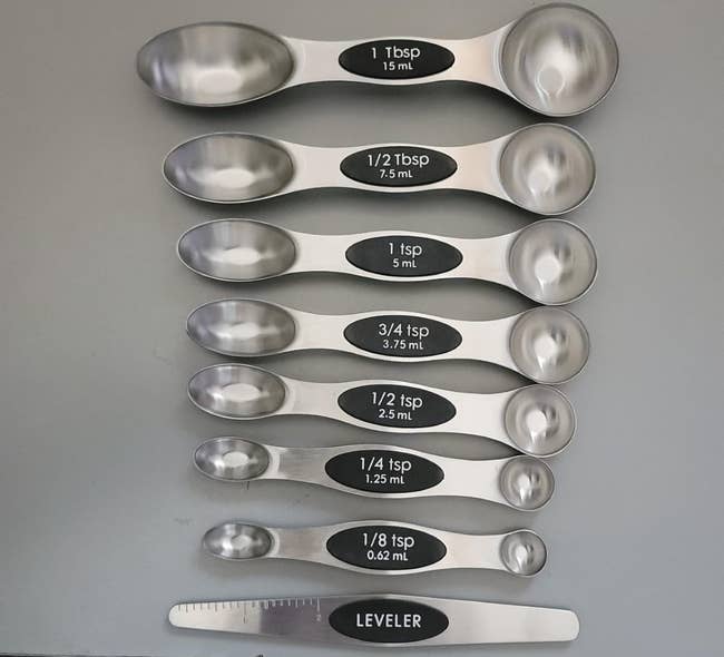 Set of 9 stainless alloy measuring spoons with labeled sizes from 1 tablespoonful to 1/8 teaspoon, including a leveler tool