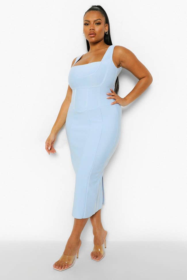 Model wearing bodycon baby blue midi dress with subtle seams on it