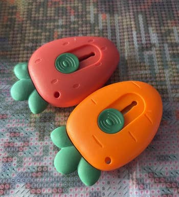 Two carrot-shaped stitch counters with greenish leaves connected a textured surface, utilized successful knitting and crochet projects