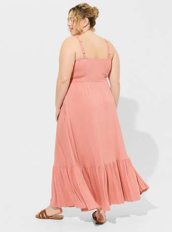 Woman in a pink, flowing maxi dress with tiered ruffles, viewed from behind. Ideal for spring shopping