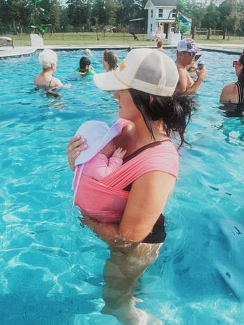 a reviewer holding their baby in the pink sling wrap