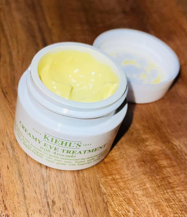 Open jar of Kiehl's Creamy Eye Treatment with Avocado connected a woody surface