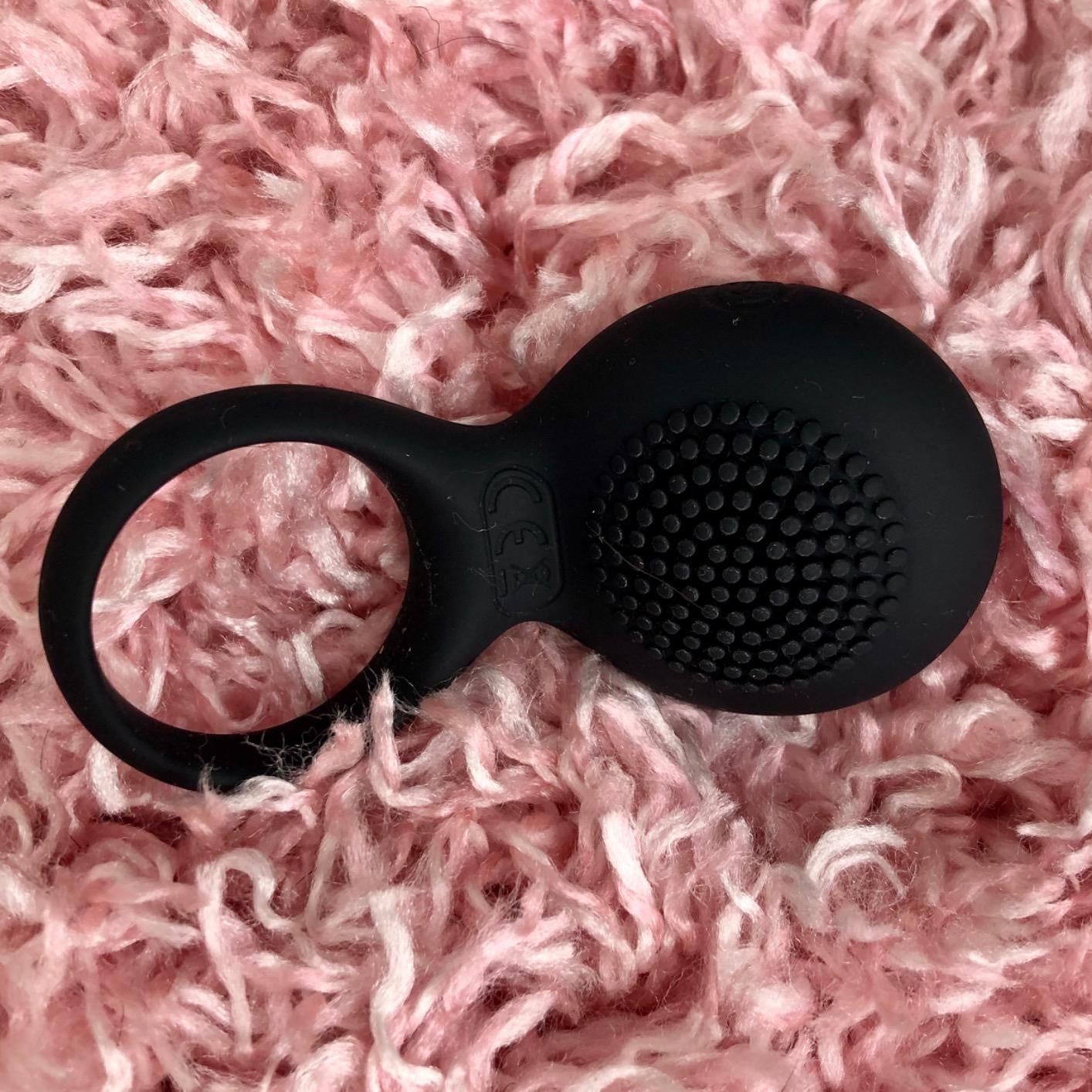 Black cock ring with vibrating textured pad on plush rug