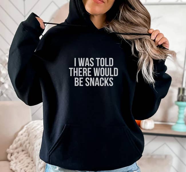 A model wearing a black hoodie with white letters that say 