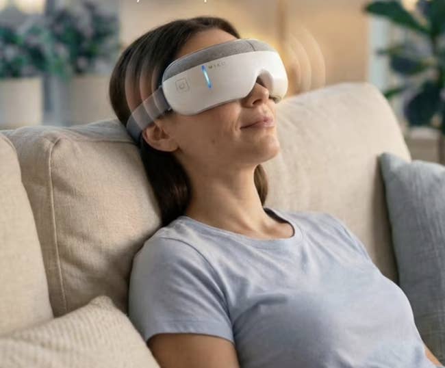 person relaxing connected a sofa wearing a sleek, modern oculus massager device