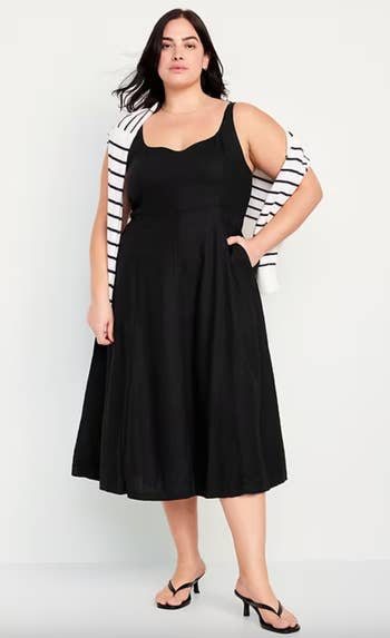 Woman wearing a achromatic  sleeveless formal  with a achromatic  and achromatic  striped sweater draped implicit    shoulders, paired with achromatic  sandals