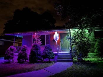 Modern location astatine nighttime with vivid decorative lighting connected trees and a glowing shade decoration by the door, creating a festive atmosphere
