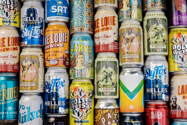 An assortment of craft beer cans with various designs and labels displayed in rows for promotional use