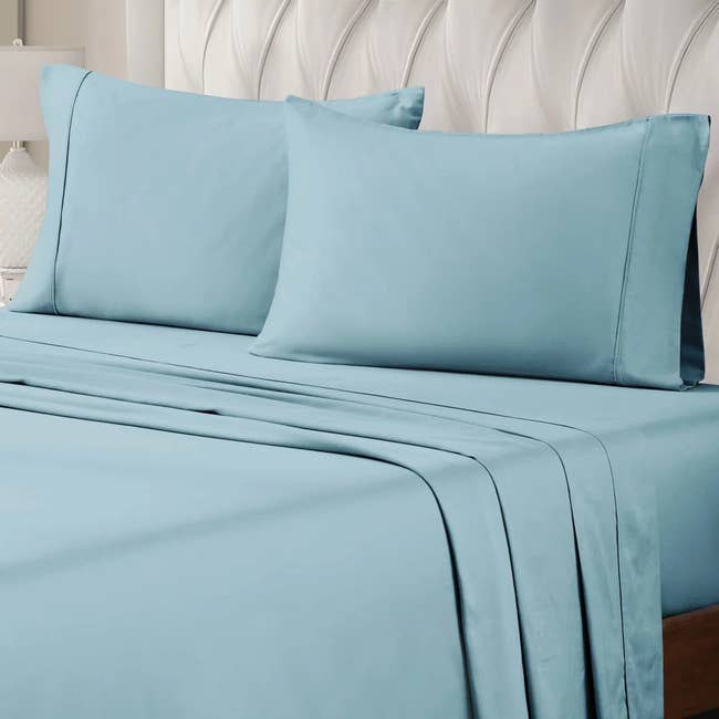A set of neatly arranged bed sheets with matching pillowcases on a luxurious tufted headboard bed