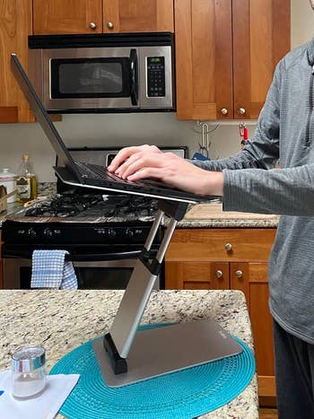 Person using a standing laptop desk on a kitchen counter for an ergonomic setup