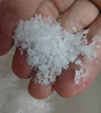 Close-up of a reviewer's hand holding Maldon sea salt, emphasizing it's large, flakey texture