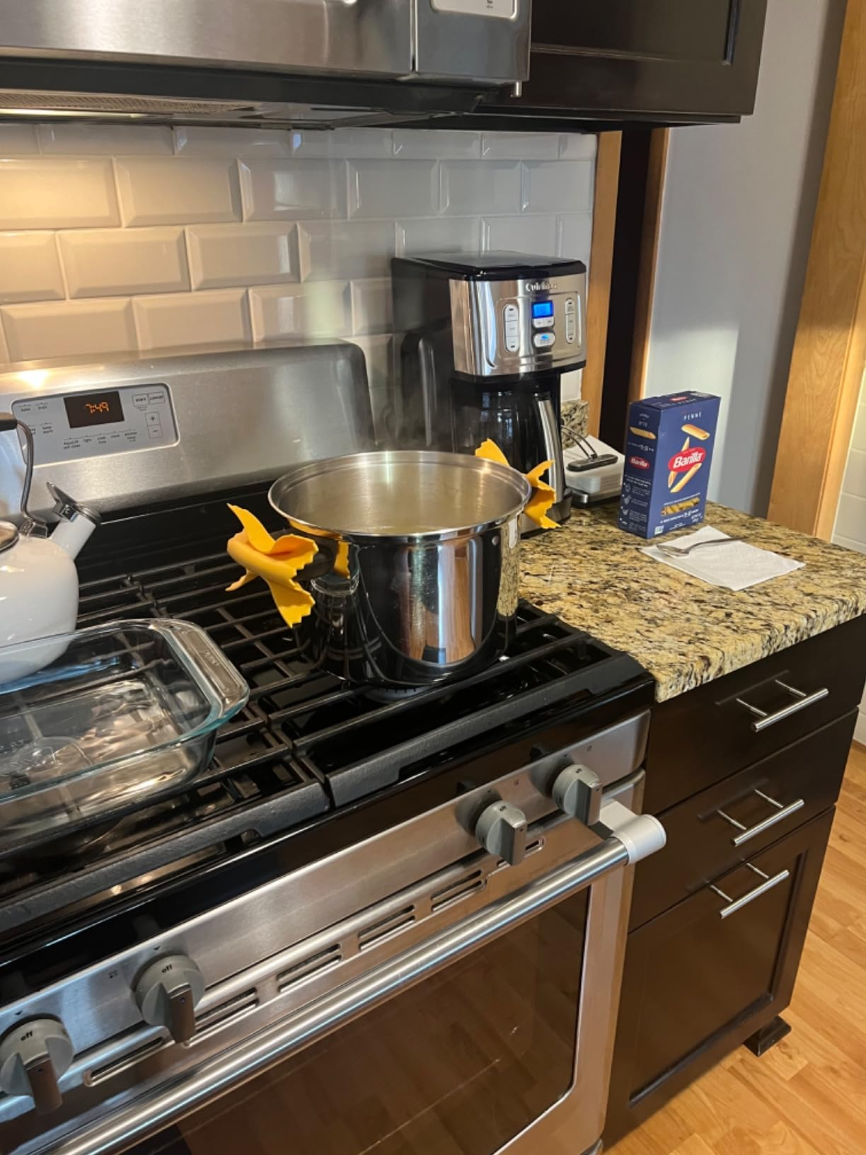 Pot of boiling h2o  connected  a stove with silicone pasta-shaped grips. Empty pasta container  and java  shaper  connected  antagonistic  suggest   cooking preparation